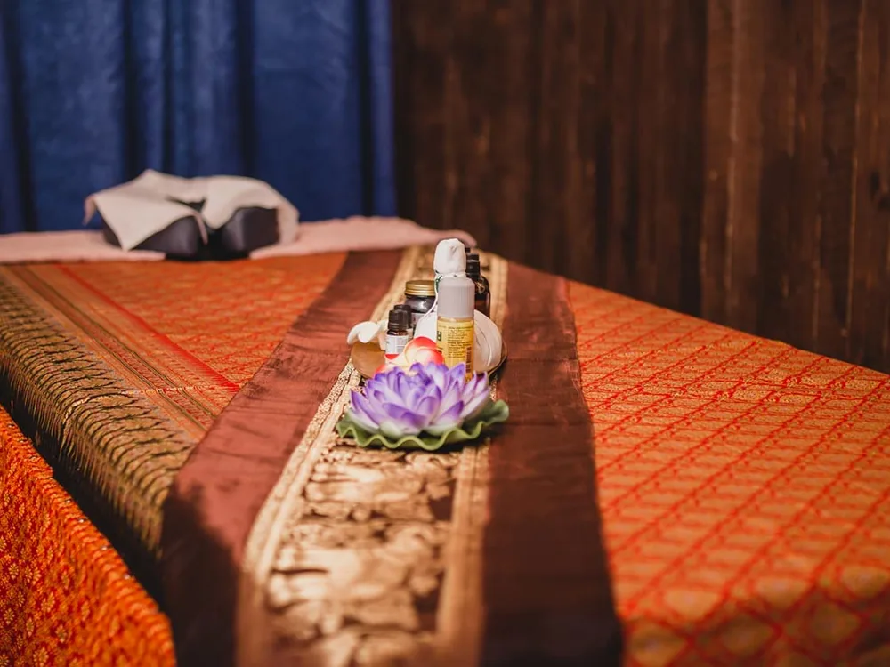 Thai spa detail with flowers, towels and warm treatment lighting